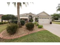 Charming single-story home featuring a lush landscaped yard, complemented by a cozy front porch and a two-car garage at 1669 Plum Branch Ter, The Villages, FL 32162