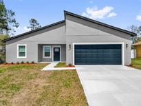 Charming single-story home featuring a modern gray exterior, blue door, and attached two-car garage at 13673 Sw 43 Cir, Ocala, FL 34473