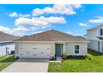 Inviting single-story home with a manicured lawn, a two-car garage, and a charming light blue front door at 1511 Finnigan Cir, Haines City, FL 33844