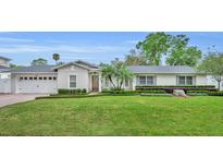 Charming single-story home featuring a beautifully landscaped front yard with lush green lawn, manicured hedges, and palm trees at 1633 Pine Ave, Winter Park, FL 32789