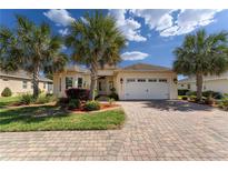 Charming single-story home with lush landscaping, a brick driveway, and a two-car garage at 5007 Belted Kingfisher Dr, Oxford, FL 34484