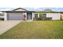 Charming single-story home featuring a well-maintained lawn, gray two car garage door, and attractive curb appeal at 5334 Mary Ann Ln, Orlando, FL 32810