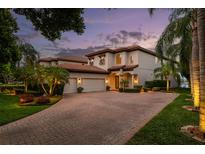 Stunning home featuring a brick driveway, lush landscaping, and a tile roof at 8161 Via Rosa, Orlando, FL 32836