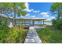View of a wooden walkway leading to a charming covered dock with a beautiful lake view at 18618 Lake Pickett Rd, Orlando, FL 32820