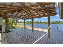 Lake house deck with a metal roof covering, ceiling fan, views of the lake, and wooden beams at 18618 Lake Pickett Rd, Orlando, FL 32820