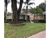 Stucco home with a barrel tile roof, mature landscaping, and a charming patio with an orange umbrella at 2108 Northumbria Dr, Sanford, FL 32771