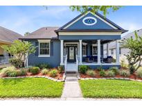 Charming blue home featuring a welcoming front porch, manicured landscaping, and classic architectural details at 13034 Royal Fern Dr, Orlando, FL 32828