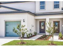 Charming townhome with a light blue garage door, manicured lawn and welcoming entrance at 914 Poppy Ln, Dundee, FL 33838