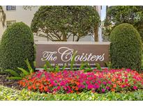 The Cloisters community sign surrounded by vibrant flowers and greenery showcases a welcoming and well-maintained neighborhood at 100 S Interlachen Ave # 107F, Winter Park, FL 32789