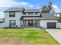 Inviting two-story home with a well-maintained lawn, an American flag, and an attached garage at 5208 Oakdale Rd, Haines City, FL 33844