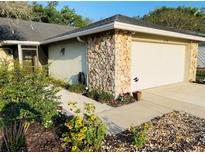 Charming home exterior with stone accents, walkway, and a beautiful landscaped front yard featuring flowers at 1034 Weathered Wood Cir, Winter Springs, FL 32708