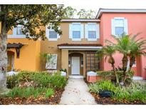 Charming multi-colored townhome with a well-maintained lawn, blooming flowers and lush landscaping at 8487 Crystal Cove Loop, Kissimmee, FL 34747