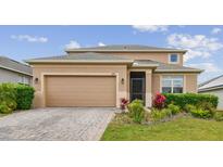 Charming two-story home featuring a well-manicured lawn, brick driveway, and attached two-car garage at 1028 Sadie Ridge Rd, Clermont, FL 34715