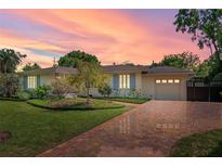 Charming single-story home with brick driveway and lush landscaping, enhanced by a beautiful sunset at 1440 Roosevelt St, Orlando, FL 32804