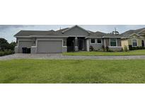 Charming single-story home with a three-car garage, well-maintained lawn, and beautiful landscaping at 1504 Cordgrass Way, Lakeland, FL 33813