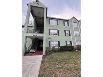 Exterior view of a light green two-story condo building with a stairway and black shutters at 2035 Dixie Belle Dr # 2035C, Orlando, FL 32812