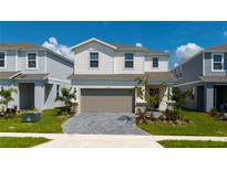 Charming two-story home with a paver driveway, attached two-car garage, and beautifully landscaped front yard at 3413 Lilac, Davenport, FL 33897