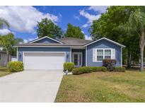 Charming single-story home with blue siding, manicured lawn, and a two-car garage at 741 Mystic Oaks Ln, Deland, FL 32724