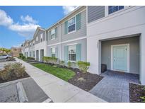 Charming townhome featuring a gray exterior, aqua shutters, and a well-maintained front lawn at 7487 Oakmoss Loop, Davenport, FL 33837