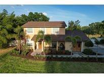 Charming two-story home with a well-manicured lawn and tropical landscaping, creating a welcoming curb appeal at 15714 Turkey Farm Rd, Minneola, FL 34715