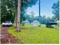 Charming single-story home with a well-maintained lawn, boat, and truck in a serene, wooded setting at 1908 W Socrum Loop Rd, Lakeland, FL 33810