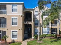 Well-maintained condo building with tan exterior, palm trees, and visible unit numbers for easy identification at 2300 Silver Palm Dr # 205, Kissimmee, FL 34747