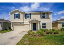 Two-story home featuring a two car garage, light yellow siding, dark shutters, and a well maintained lawn at 4423 Blackbird St, Kissimmee, FL 34746