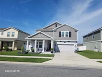 Charming two-story home with gray siding, white trim, covered front porch, and well-manicured landscaping at 1803 Perch Hammock Loop, Groveland, FL 34736