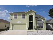 Charming two-story home featuring an arched entryway and an attached two-car garage at 339 Sigmund Loop, Davenport, FL 33837