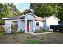 Charming single-story home with a bright red front door and an attached garage at 517 Walnut St, Auburndale, FL 33823