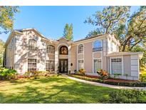 Stately home featuring a grand entrance, manicured lawn, and lush landscaping at 1374 Century Oak Dr, Ocoee, FL 34761