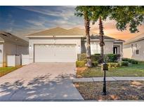 Charming single-story home with a two-car garage, well-manicured lawn, and a brick-paved driveway at 217 Herring St, Davenport, FL 33897