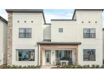 Modern two-story home featuring a stylish facade, covered entryway, and carefully landscaped front yard at 235 Villa Domani Cir, Davenport, FL 33896