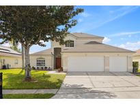 Charming two-story home featuring a three-car garage, manicured lawn, and mature landscaping at 239 Longhirst Loop, Ocoee, FL 34761