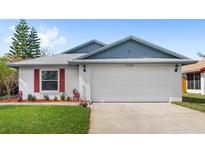 Charming single-story home with a two-car garage, red shutters, and well-manicured front lawn at 3192 Running Deer Path, Kissimmee, FL 34746