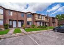 Brick townhome featuring a lush lawn, manicured landscaping, and ample parking at 5060 Downing St # 6, Orlando, FL 32839