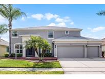 Charming two-story home featuring a three-car garage, well manicured lawn and mature palm trees at 1712 Boat Launch Rd, Kissimmee, FL 34746