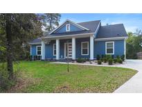 Charming blue home featuring a covered front porch and well-manicured lawn, perfect for curb appeal at 34 Jackson Cir, Winter Springs, FL 32708
