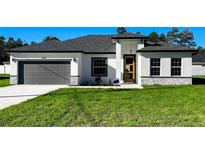 Charming single-story home featuring a gray garage door, stone accents, and a welcoming front yard at 4634 Sw 170Th Road, Ocala, FL 34473