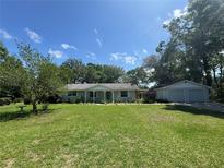 Charming single-story home with well-maintained lawn, mature trees, and a detached two car garage at 12015 Se 72Nd Court Rd, Belleview, FL 34420