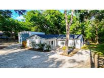 Charming home with a gravel driveway and a detached garage surrounded by lush greenery at 30542 Hoylake St, Sorrento, FL 32776
