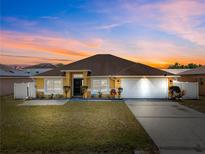 Charming home featuring a well-manicured lawn, two-car garage, and inviting curb appeal beneath a vibrant sunset sky at 408 Magpie Ct, Kissimmee, FL 34759