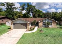 Charming single-story home featuring a well-manicured lawn, stone accents, and a two-car garage at 735 Oak Ter, Orange City, FL 32763
