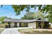 Charming single-story home with a well-manicured lawn, blue front door, and a curved driveway leading to the garage at 1025 Winter Springs Blvd, Winter Springs, FL 32708