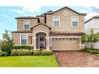 Charming home featuring a two-car garage, manicured lawn, and a stone and stucco exterior at 1518 Rolling Fairway Dr, Davenport, FL 33896