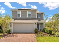 Charming two-story home featuring a spacious two-car garage, brick paved driveway, and professionally landscaped yard at 1559 Scrub Jay Ct, Deland, FL 32724