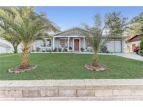 Charming home featuring a well-manicured lawn, vibrant landscaping, and two lovely palm trees at 1905 Lady Ave, Ocoee, FL 34761
