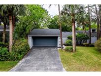 Charming home featuring a two car garage with a dark blue door, beautiful landscaping, and a paved driveway at 207 Sweet Gum Way, Longwood, FL 32779
