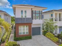 Contemporary two-story home featuring a gray garage door, modern windows and manicured landscaping at 748 Desert Mountain Ct, Reunion, FL 34747