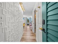 Bright condo hallway featuring stylish wall decor and wood-look floors leading to an inviting living space with ocean views at 800 N Atlantic Ave # 417, Daytona Beach, FL 32118